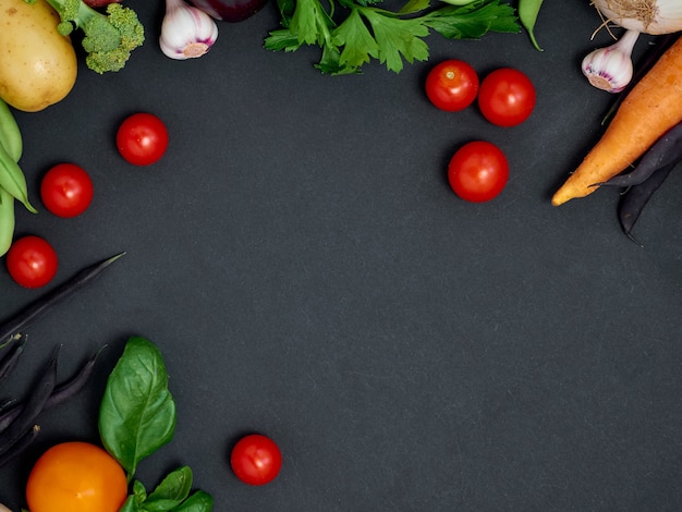 Cadre de divers légumes sur fond sombre, vue de dessus.