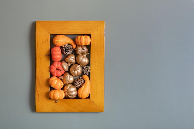 Cadre doré avec des citrouilles, des roses et des feuilles d'érable Concept esthétique minimaliste d'automne