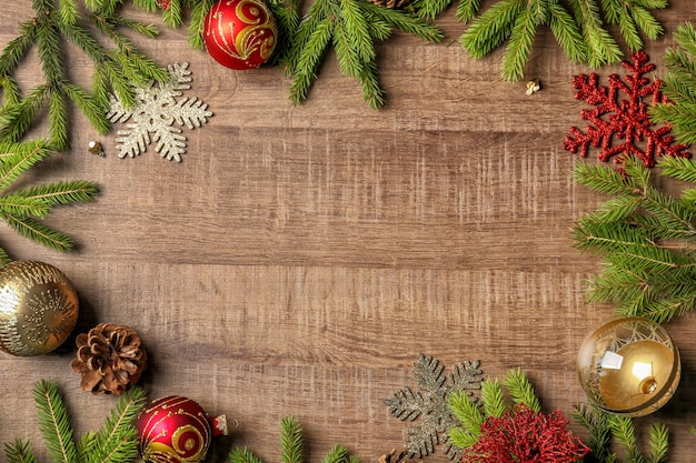 Cadre fait de branches de sapin et décor de Noël sur fond de bois