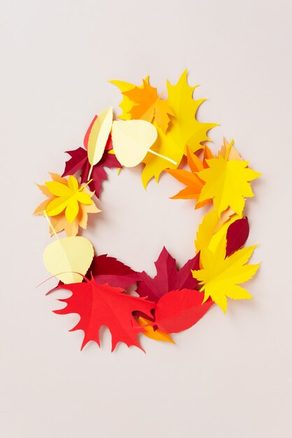 Un cadre fait de feuilles d'automne sur fond beige. Les feuilles sont découpées dans du papier