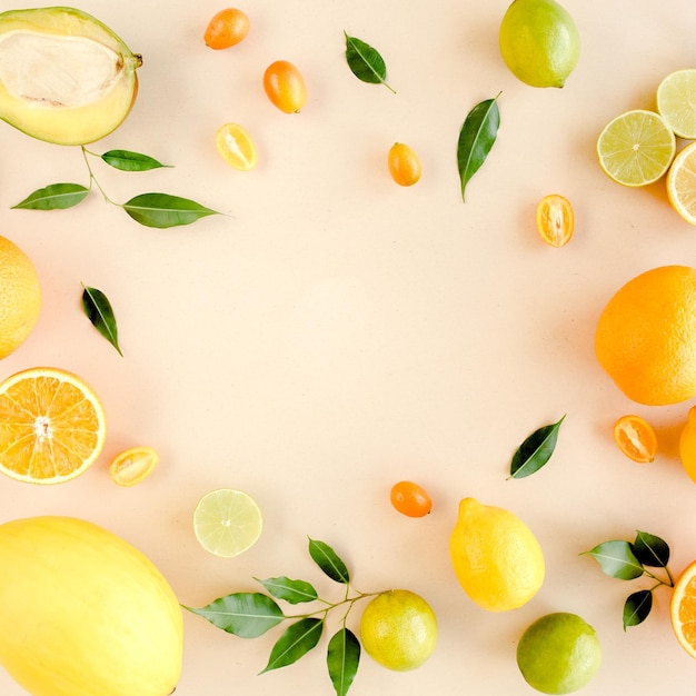 Cadre fait de fruits tropicaux d'été orange citron citron vert mangue sur fond jaune concept alimentaire plat