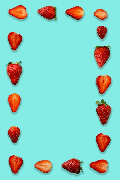 Cadre fait de groupe frais Fraises juteuses mûres isolées sur fond bleu. Mise à plat.