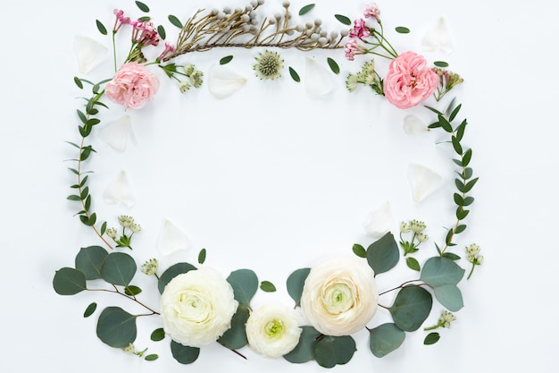 Cadre de fleurs avec des branches fraîches de roses en forme de pion et de feuilles d'eucalyptus isolés sur fond blanc, plat poser et vue de dessus