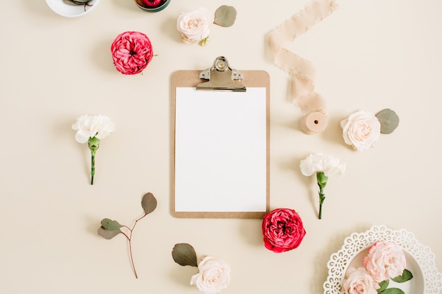 Cadre Floral Plat Avec Presse-papiers Vierge, Boutons De Fleurs Roses Rouges Et Beiges, Oeillet Blanc, Eucalyptus, Ruban Sur Fond Pastel Beige Pâle. Vue De Dessus