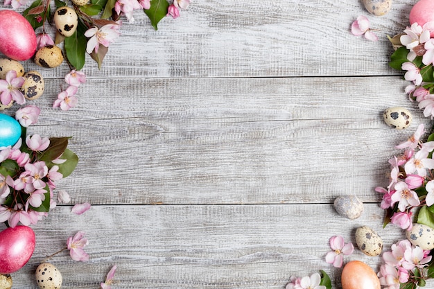 Cadre de fond de fleurs de pommier rose, oeufs de caille et oeufs de poule de Pâques colorés