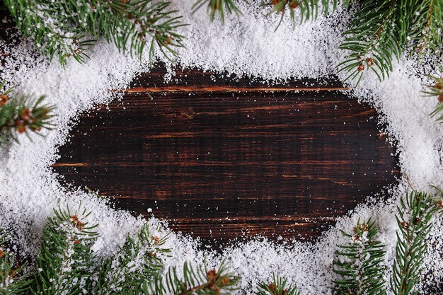 Cadre de fond de Noël, arbres de Noël verts sur une table en bois, parsemé de neige blanche, espace copie, vue de dessus.