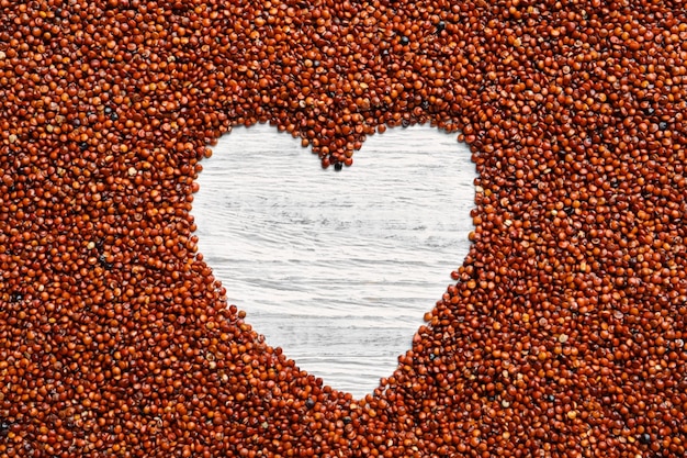 Cadre en forme de coeur composé de graines de quinoa bio sur fond de bois