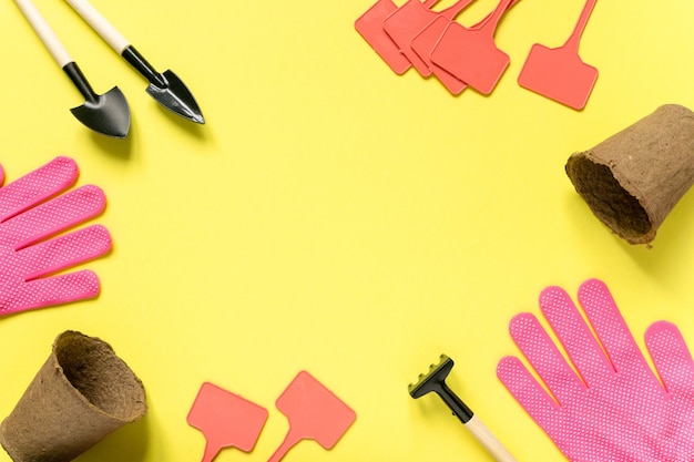 Cadre de fournitures de jardinage. Outils, pots de tourbe, gants et assiettes de semis sur une surface jaune, espace pour le texte.