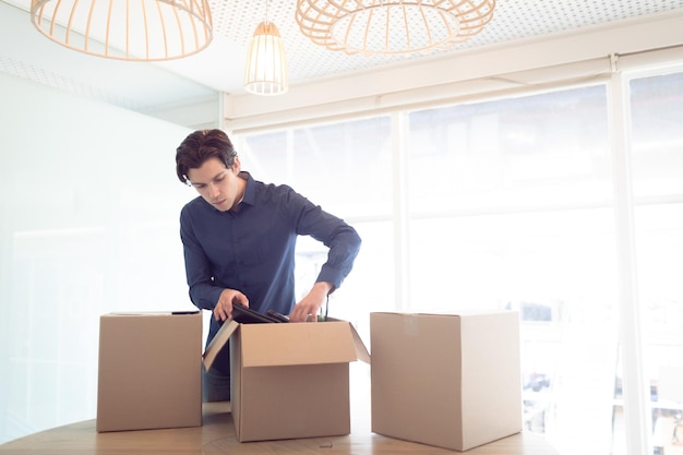 Un cadre masculin enlevant des choses d'une boîte en carton dans son bureau