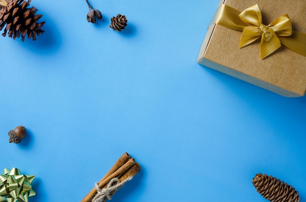 Cadre de Noël avec boîte-cadeau cônes de conifères cannelle et ornements sur fond de papier bleu