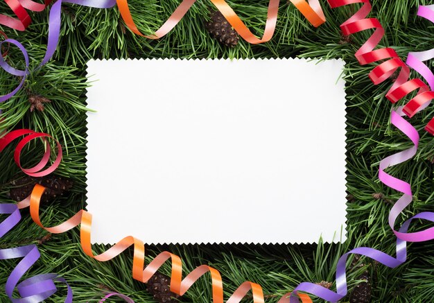 Cadre de Noël avec des branches décorées de pin et une feuille de papier blanc. Copiez l'espace pour le texte de vacances, de félicitations ou de publicité