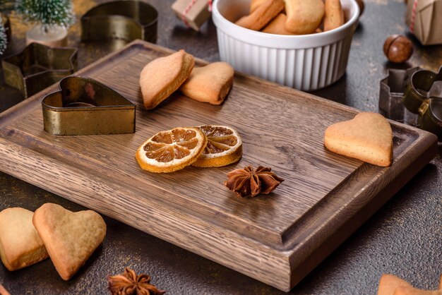 Cadre de Noël avec des branches de sapin, des biscuits de pain d'épice, des épices, des anneaux d'orange séchés et des jouets de Noël sur fond de pierre