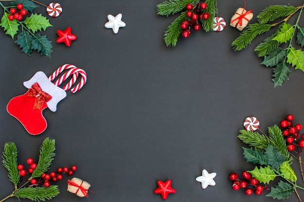 Cadre de Noël avec des branches de sapin, des bonbons, des cadeaux et des étoiles sur l'obscurité