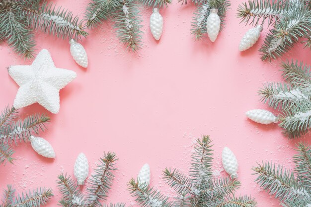 Cadre de Noël composé de branches de sapin et de neige sur fond de rose.xmas. Lay plat. Vue de dessus avec espace de copie