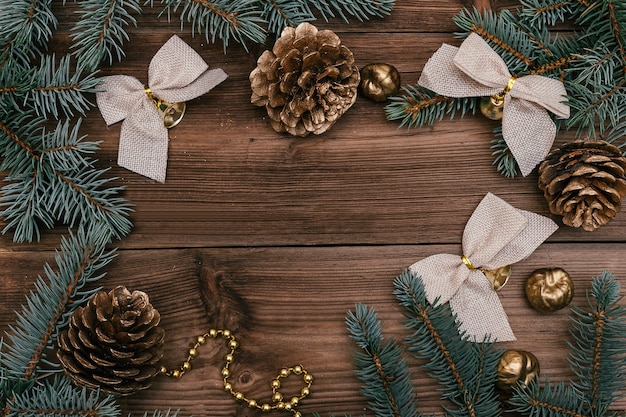Cadre de Noël fait de branches de sapin bleu, cônes dorés et décorations de vacances.