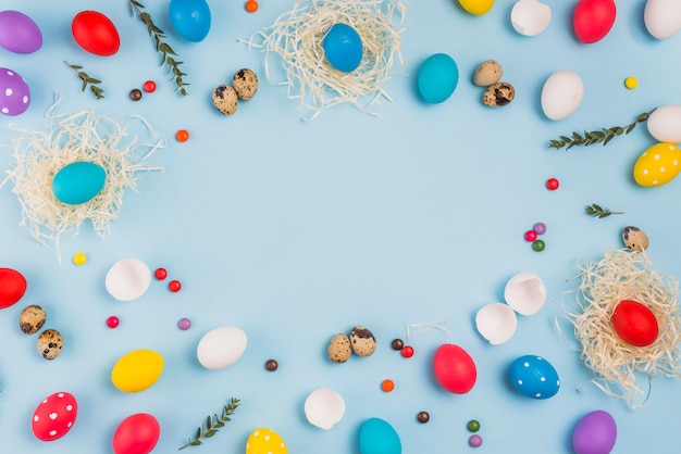 Photo cadre d'oeufs de pâques dans des nids et des bonbons