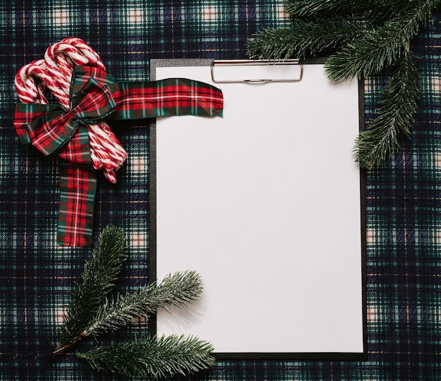 Cadre en papier de Noël Nouvel An, style flatley avec une vue de dessus avec des décorations de Noël faites de cannes de Noël et de branches d'épinette sur fond dans une cage. place pour votre texte.