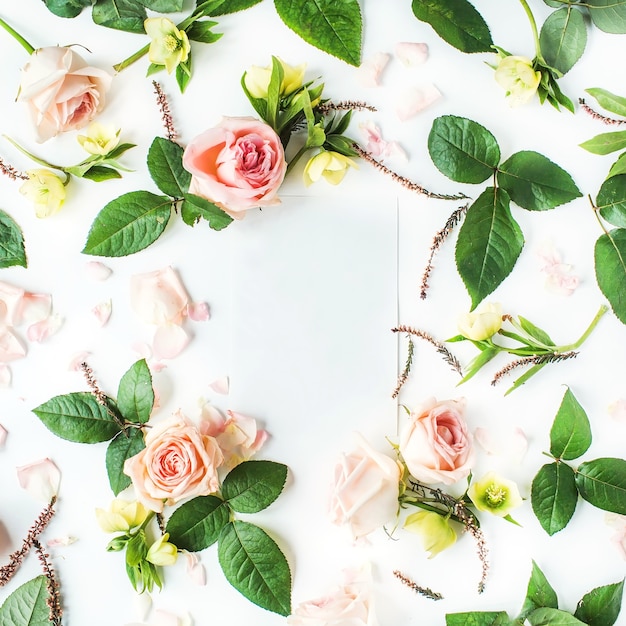 Cadre de papier vierge, roses roses, branches, feuilles et pétales isolés