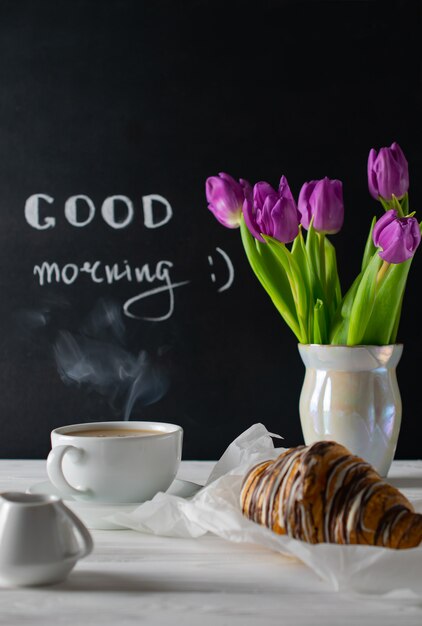 Cadre de petit-déjeuner positif et joyeux avec bouquet de tulipes, café et croissant