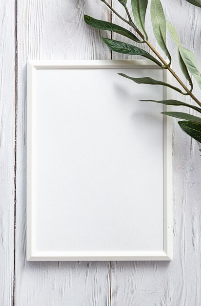 Cadre photo blanc avec un brin d'eucalyptus sur une table en bois blanc