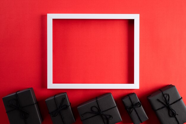 Cadre photo blanc avec un coffret noir sur fond rouge. Concept Black Friday