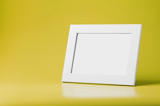 Cadre photo blanc sur surface jaune avec espace libre. Concept minimaliste