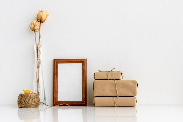 Cadre photo en bois et plantes séchées dans des vases sur fond blanc Disposition d'été douce et minimaliste Vierge pour une carte postale Intérieur pour le design