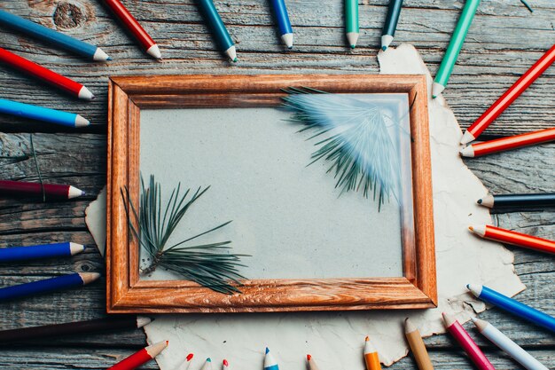 Photo cadre photo de composition de noël sur la table en bois avec des branches d'arbres avec des crayons