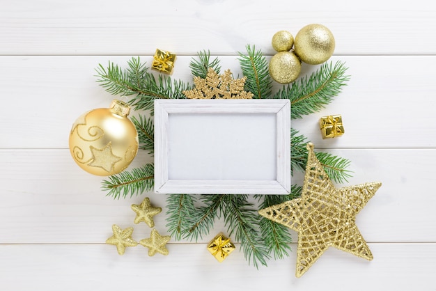 Cadre photo avec décoration de Noël, avec des boules de couleur dorée et une étoile sur une table en bois blanc. Vue de dessus, cadre pour copier l'espace