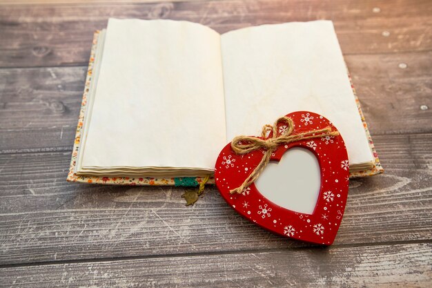 un cadre photo en forme de coeur rouge se trouve sur un cahier ouvert