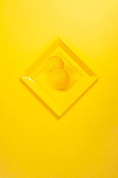 Cadre photo jaune moderne sur mur jaune en forme de losange avec une photo de deux boules jaunes