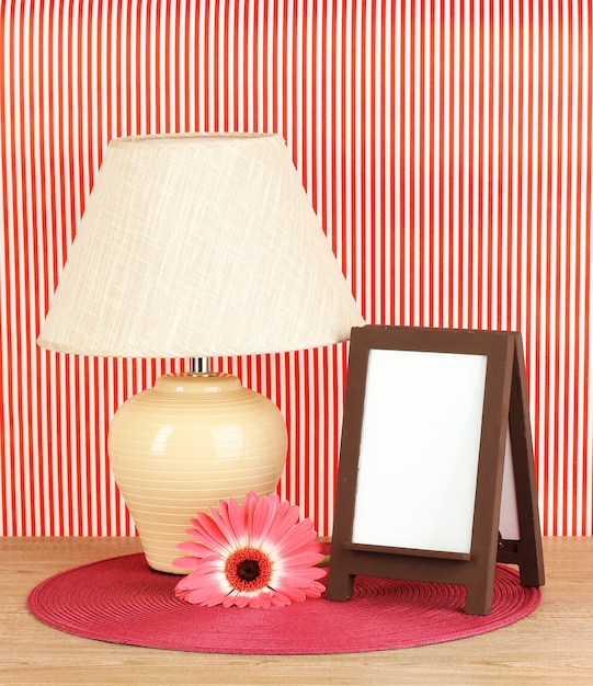 Cadre photo marron et lampe sur table en bois sur mur rayé rouge