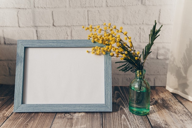 Cadre photo et une petite bouteille de mimosa sur un mur de briques