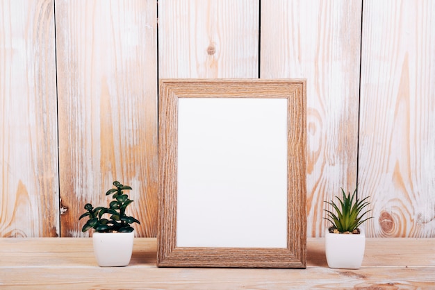 Cadre photo vide avec deux plantes succulentes en plus sur une table en bois