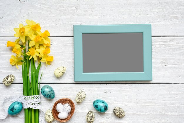 Cadre photo vierge avec des oeufs de Pâques et des fleurs de printemps