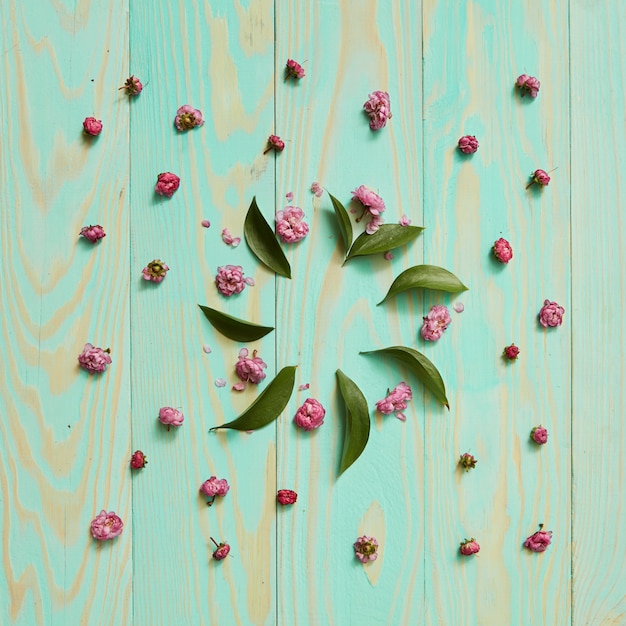 Cadre rond de fleurs et de feuilles sur un fond bleu en bois à plat