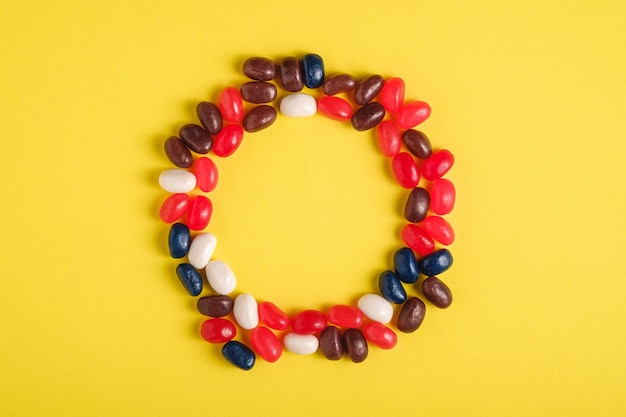 Cadre Rond De Jelly Beans Colorés Juteux De Fruits Sucrés Sur Une Surface Jaune Vif, Vue De Dessus Copie Espace