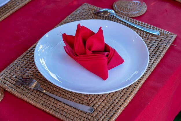 Cadre de table élégant avec fourchette cuillère assiette blanche et serviette rouge au restaurant Belle table à manger avec argenterie et serviettes disposées