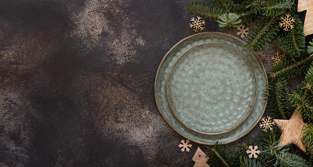 Cadre de table de fête avec des branches de sapin et des décorations de Noël rustiques sur la vue de dessus de table sombre