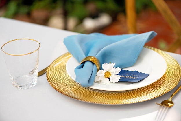Cadre de table de mariage élégant et chic dans des couleurs or et bleu et des fleurs fraîches. Mise au point sélective douce.