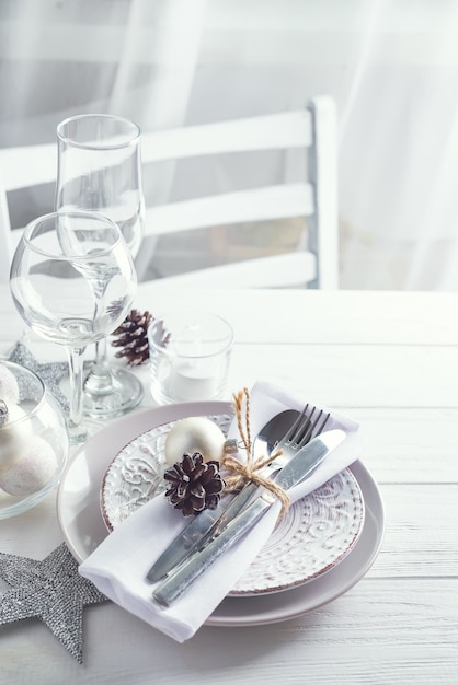 Cadre de table de Noël argenté et blanc avec décorations de Noël au-dessus de la fenêtre