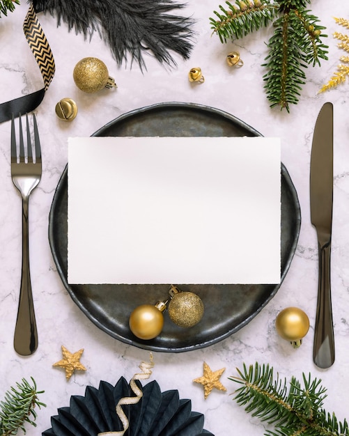 Photo cadre de table de noël noir et doré avec des ornements de carte et des branches de sapin maquette