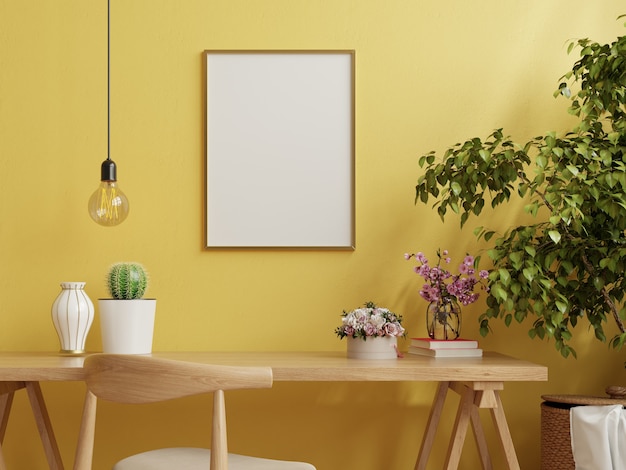 Cadre sur table de travail à l'intérieur du salon sur mur jaune vide
