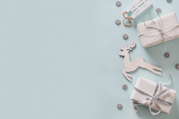 Cadre de vacances de Noël avec des cadeaux, un décor en bois blanc, des cerfs et des flocons de neige