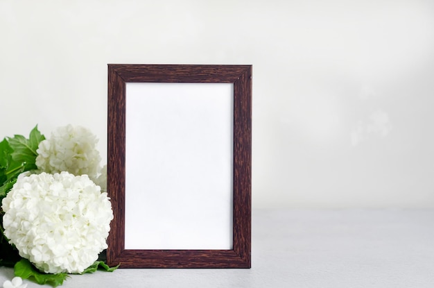 Cadre vide et bouquet d'hortensia fleur blanche dans un vase sur fond gris