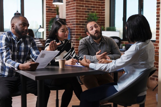 Des cadres dirigeants multiethniques interviewant un candidat afro-américain discutant d'un curriculum vitae recrutant un employeur pour un emploi dans les ressources humaines dans le bureau d'une entreprise en démarrage. Concept de processus d'embauche