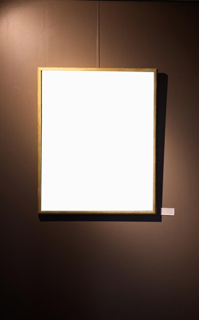 Des cadres d'images blancs sur le mur brun avec une lampe lumineuse dans la galerie mock-up