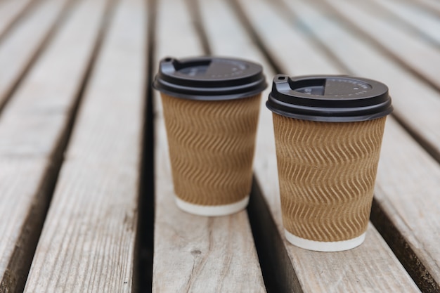 Café aromatique chaud dans des gobelets en papier avec des couvercles noirs