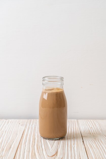 Café au lait en bouteille sur table en bois