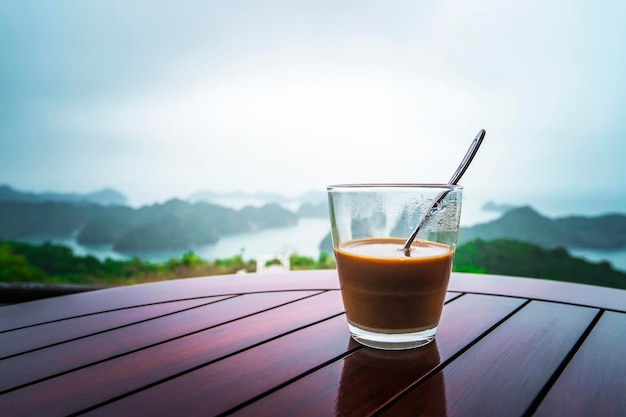 Café au lait chaud dans le style vietnamien Petit-déjeuner avec une belle vue contre les rochers sortant de l'eau dans la mer Baie d'Ha Long dans le nord du Vietnam